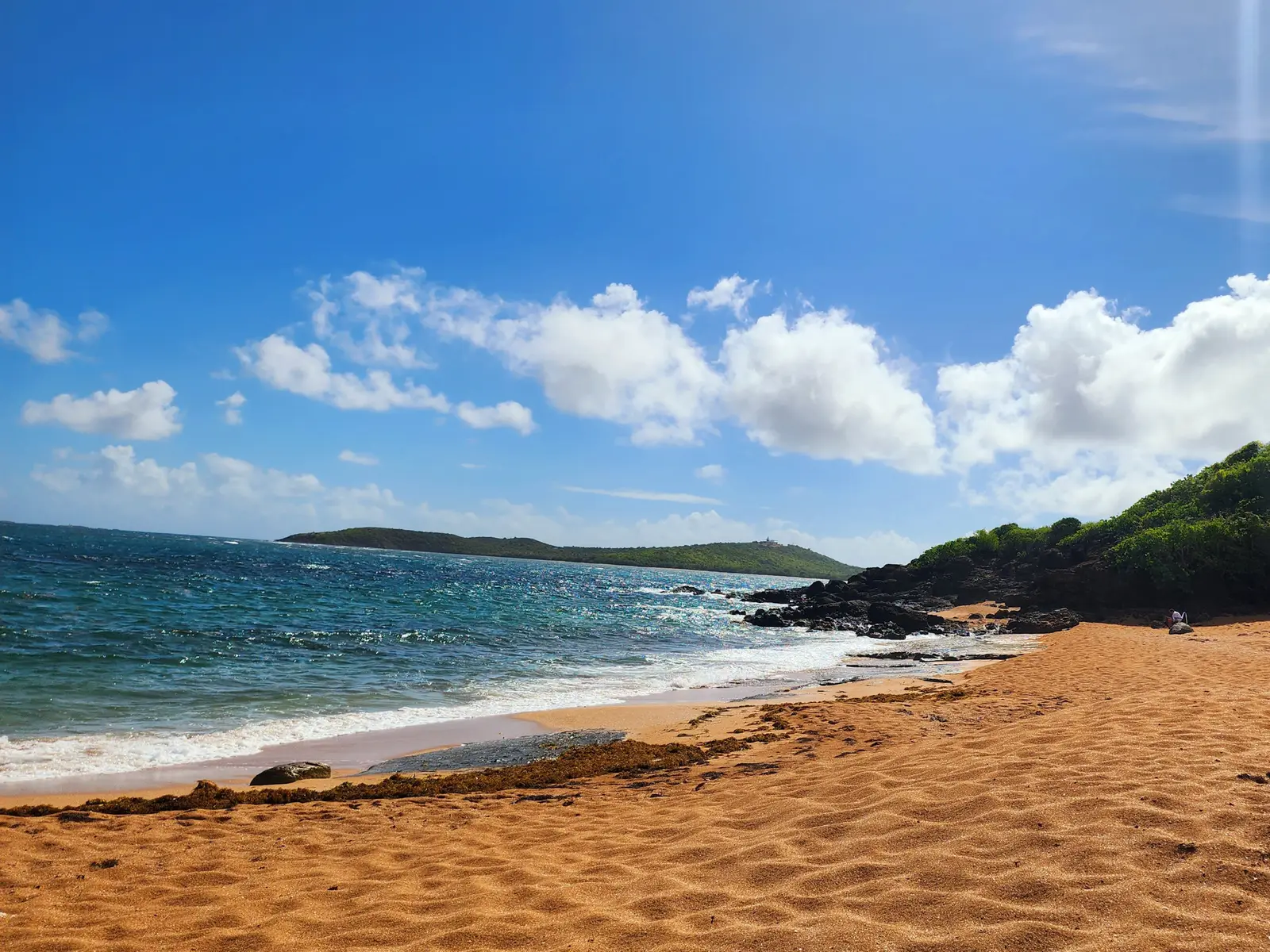 The beach is crescent shaped with rocky cilffs at each end.